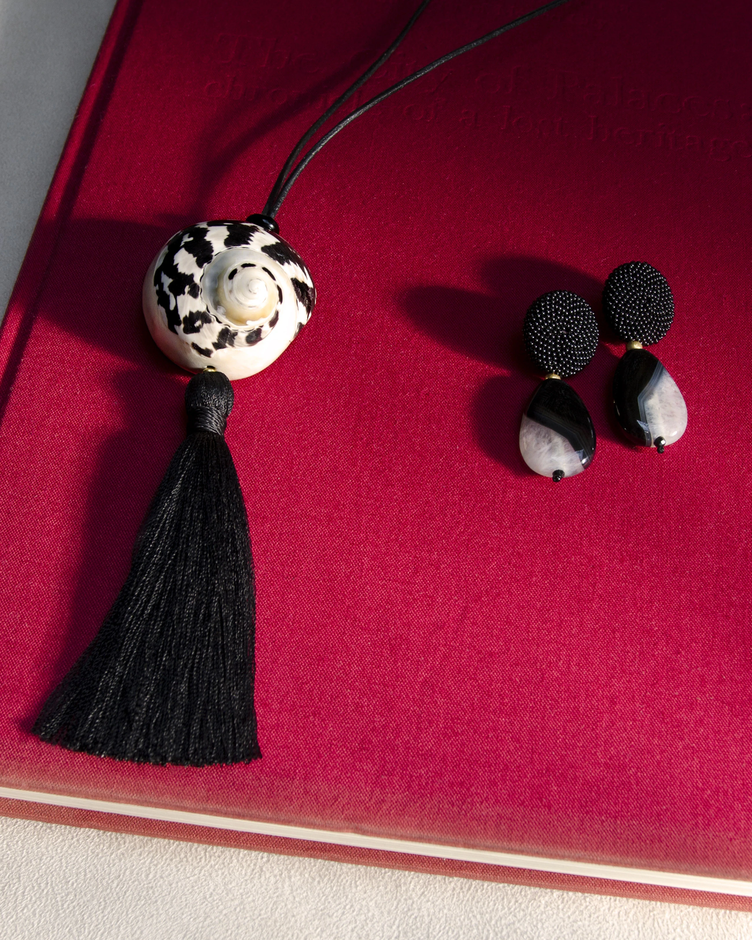 Black & White Shell Necklace With Tassel — Black & white shell necklace with long silky tassel on leather cord, styled beside black beaded drop earrings